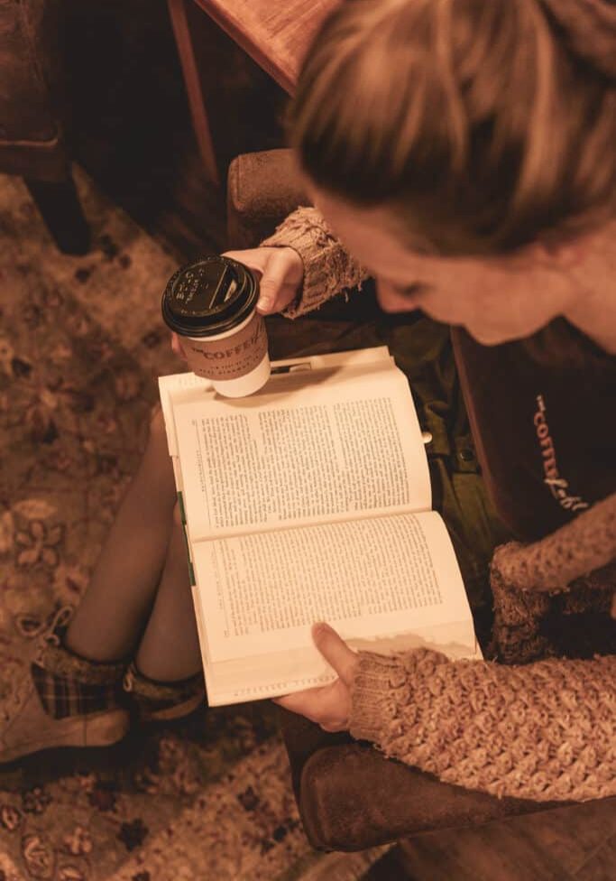 Woman drinking coffee and reading a book at the Coffee Loft